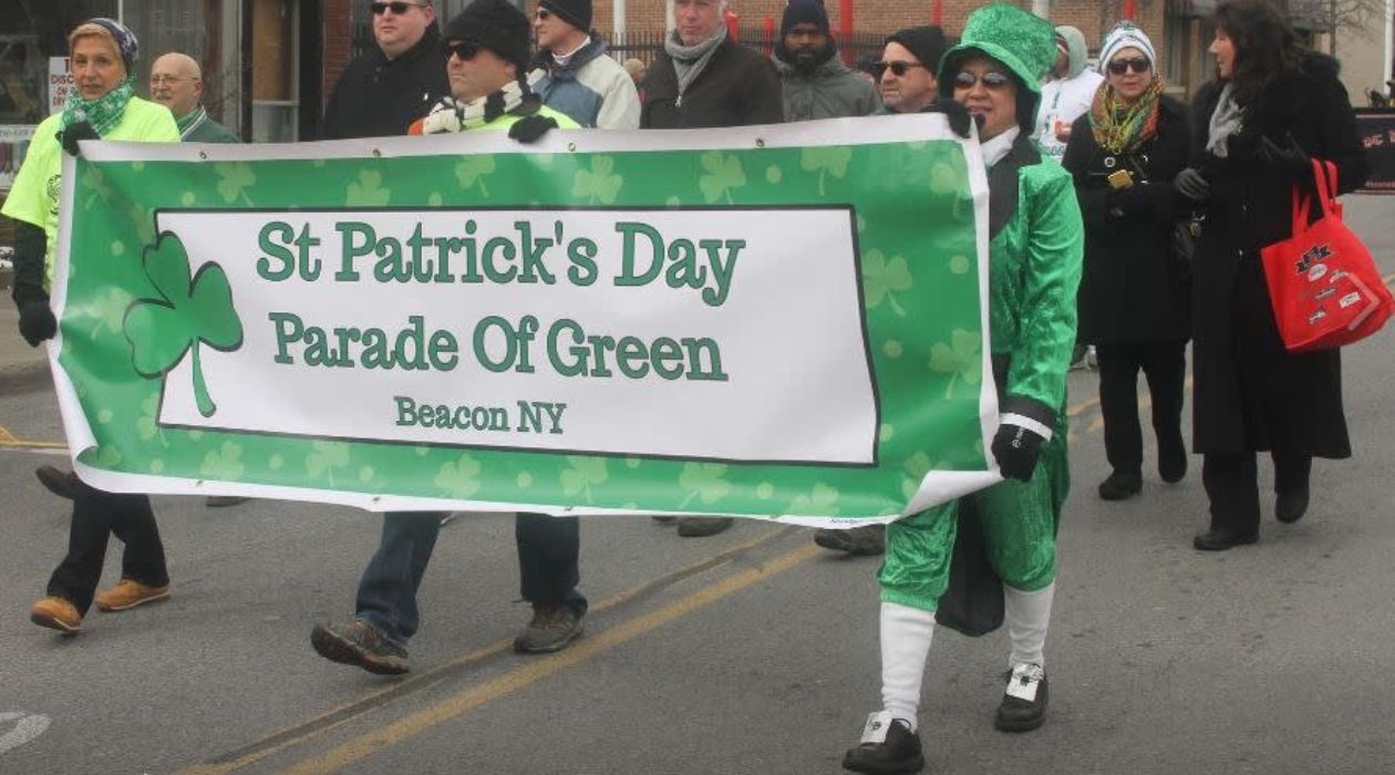 Two parade participants dressed in green carry the banner at the front of the St. Patricks Day Parade of Green in Beacon